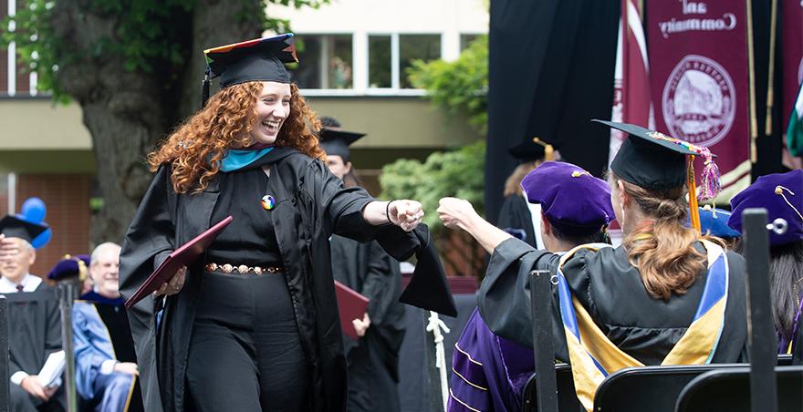 一名学生在SPU获得毕业证书后，戴着学士帽和学士服的学生互相握手